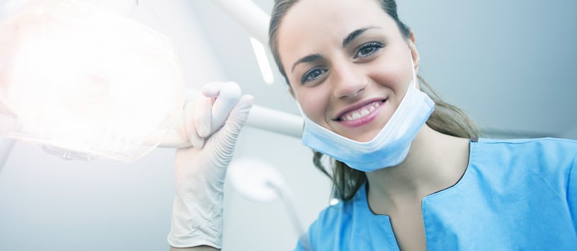 A dental assistant shining a light at the camera 